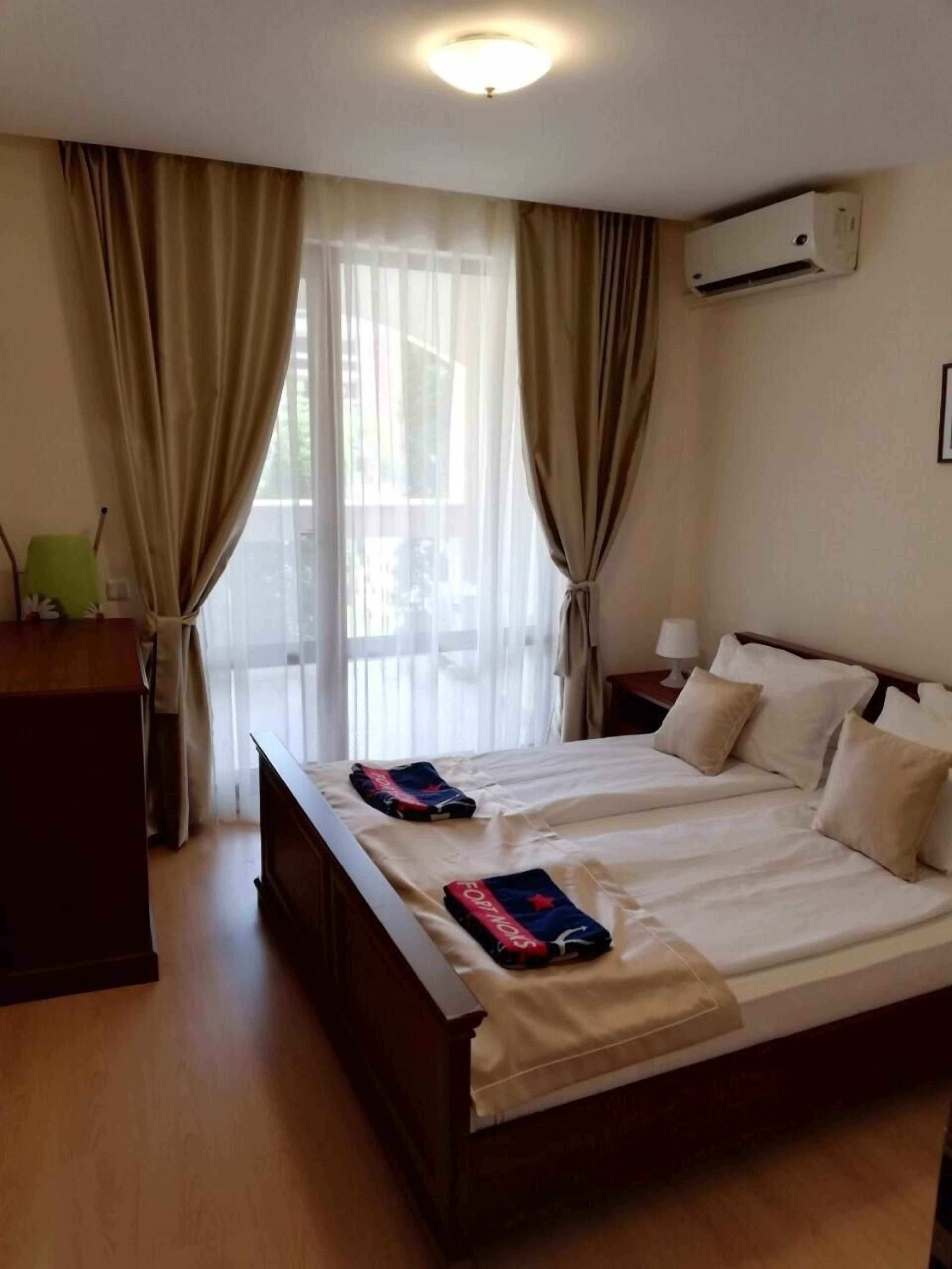 Een hotelkamer met een tweepersoonsbed, een bureau, een airconditioner en een raam met gordijnen.