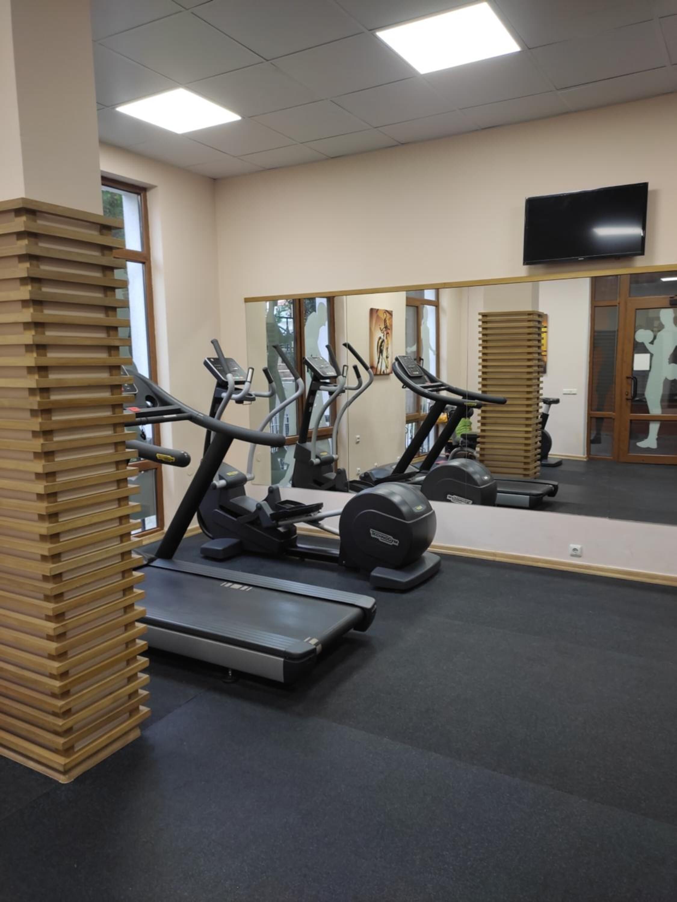 A gym with treadmills, stationary bikes, and a mirrored wall.