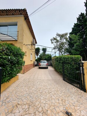 A paved driveway leading to a house with a tiled roof and a parked car.