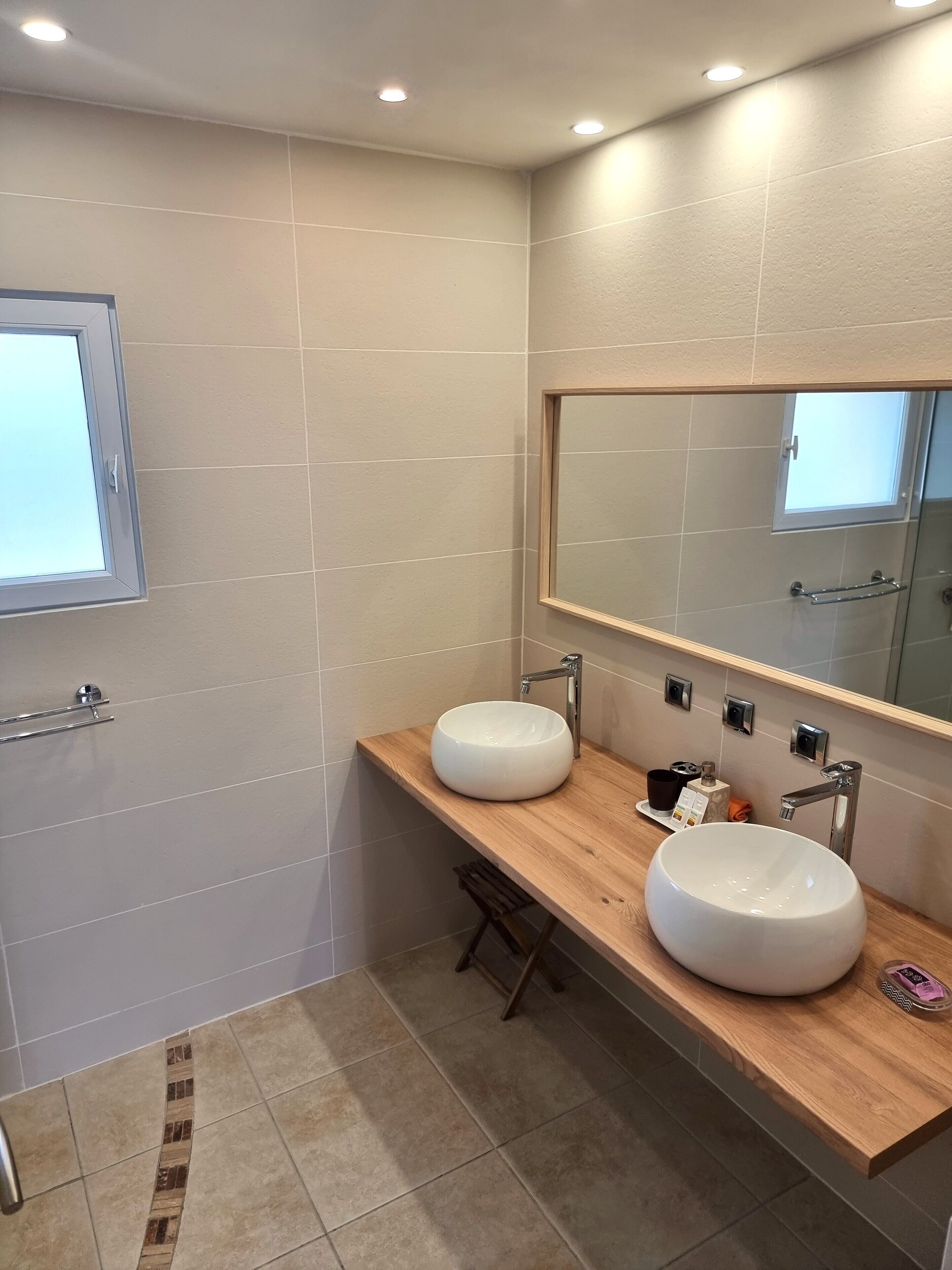A modern bathroom with two sinks, a large mirror, and a window.