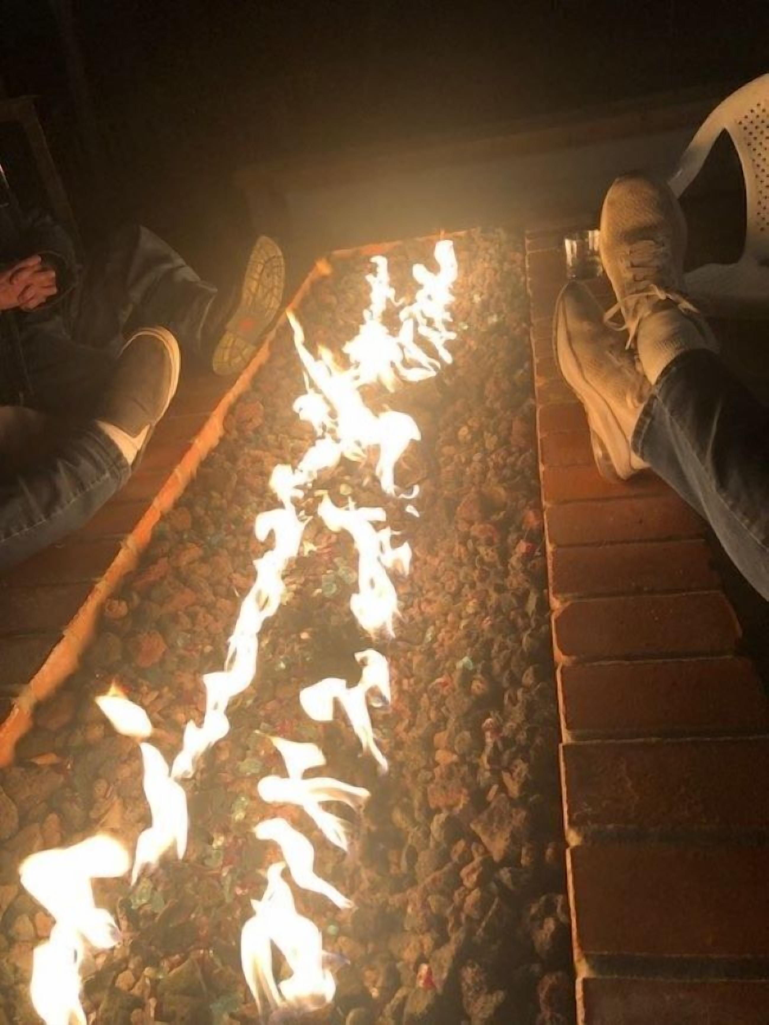 A close-up of a fire feature with flames, surrounded by a stone surface.