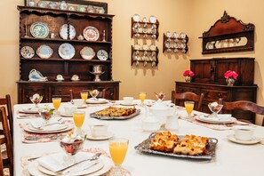 A dining room with a long table set for breakfast, including plates, cups, and a variety of dishes.