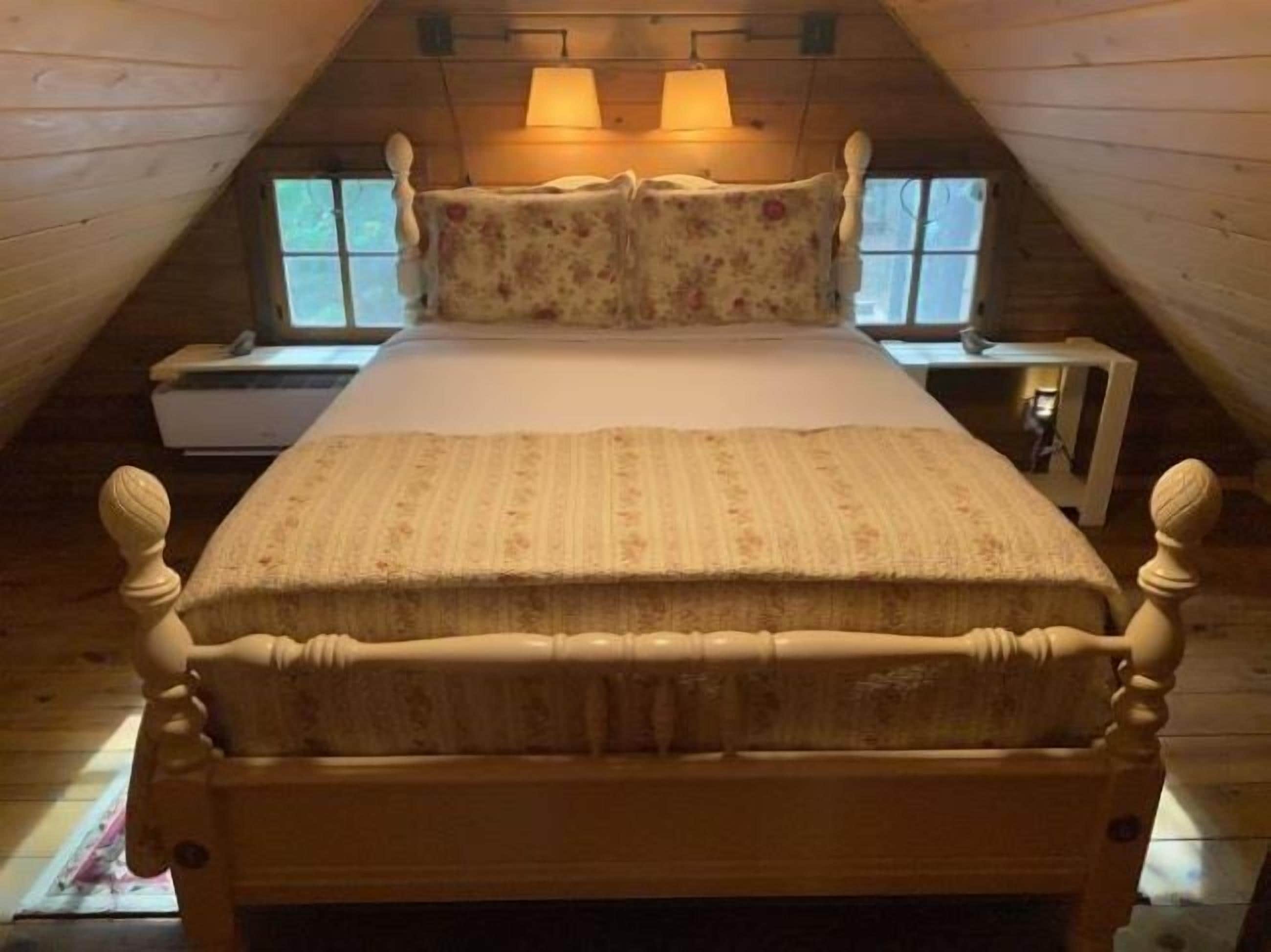 A wooden room with a bed, two nightstands, and two lamps.