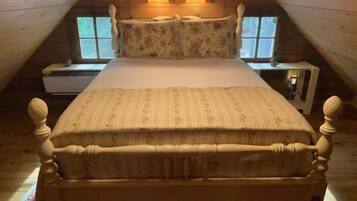 A wooden room with a bed, two nightstands, and two lamps.