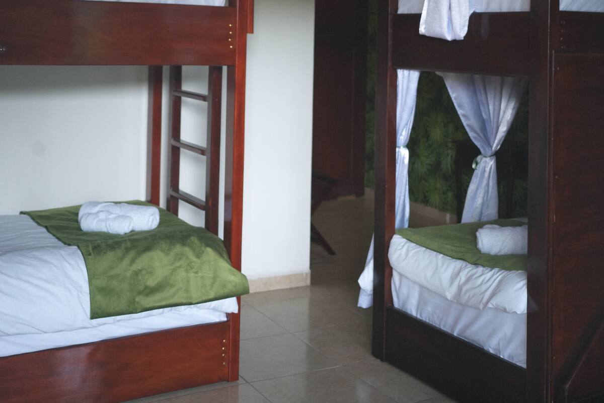 Una habitación con literas, techo de madera y piso de baldosas.