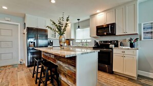 A modern kitchen with a central island, stainless steel appliances, and light-colored cabinetry.