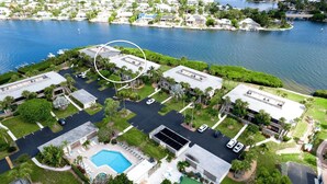 An aerial view of a residential area with a swimming pool, multiple buildings, and a marina.