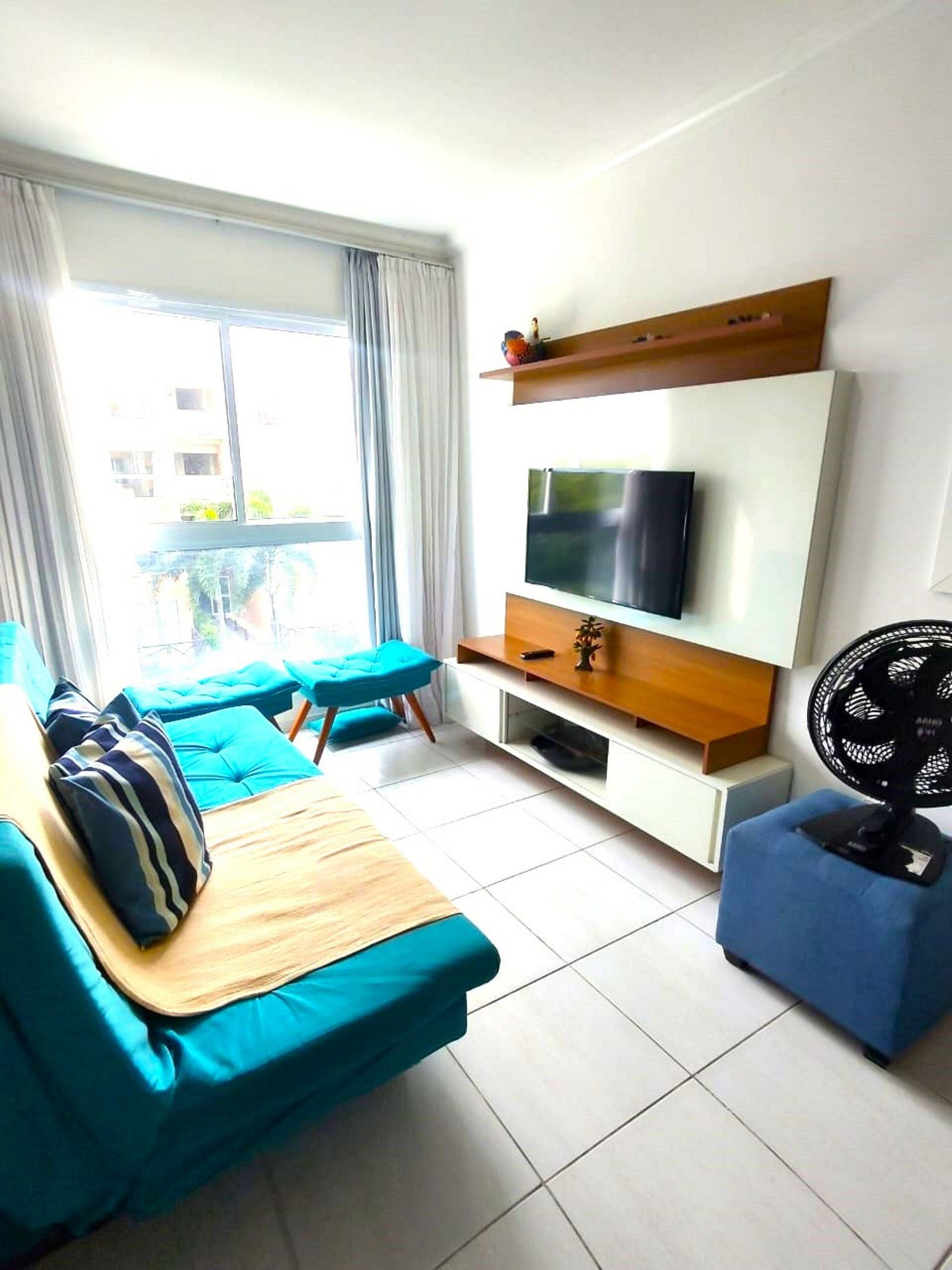 A modern living room with a sofa, TV, and a fan.