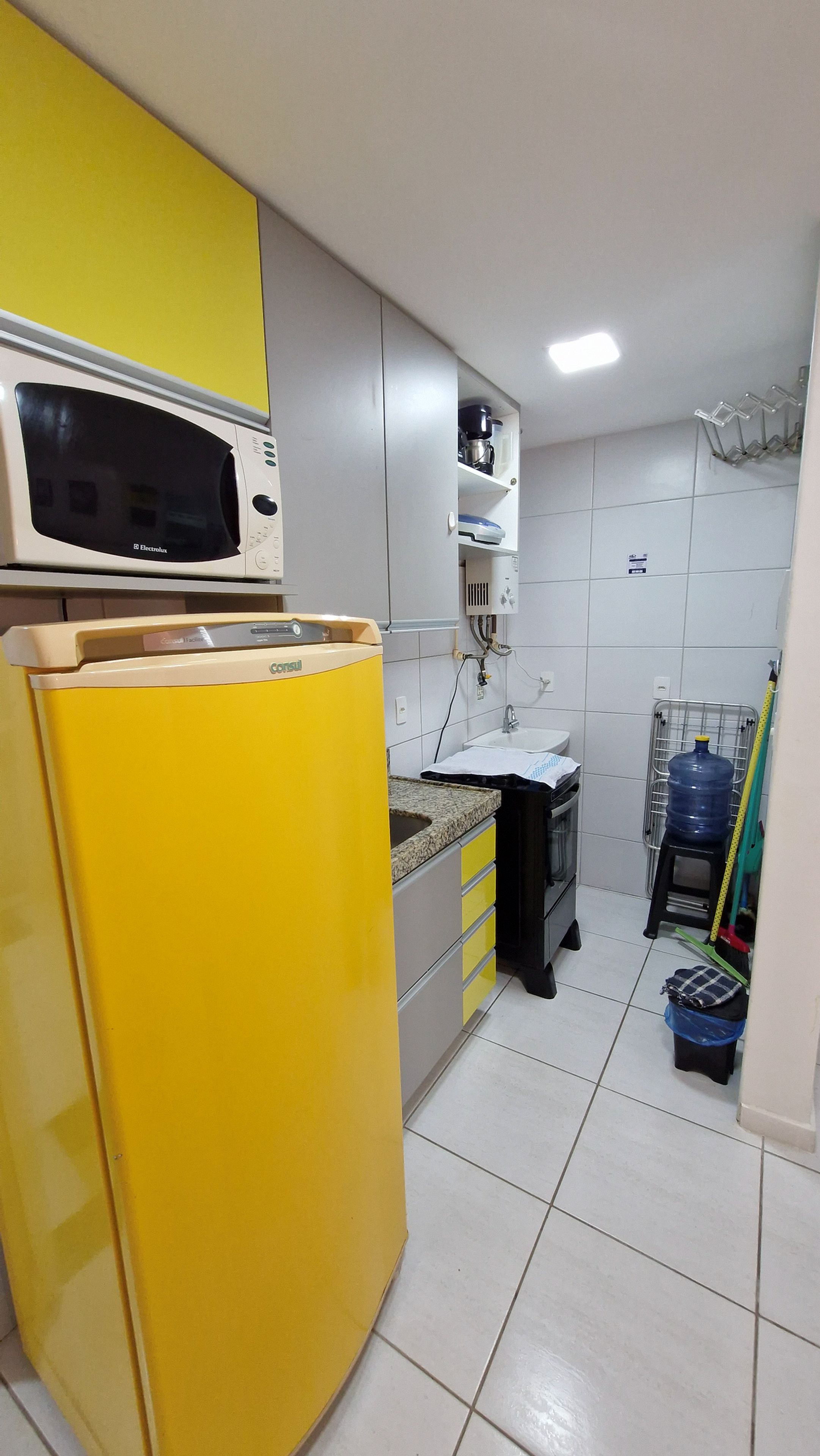 A compact kitchen with a yellow refrigerator, a microwave, and a sink.