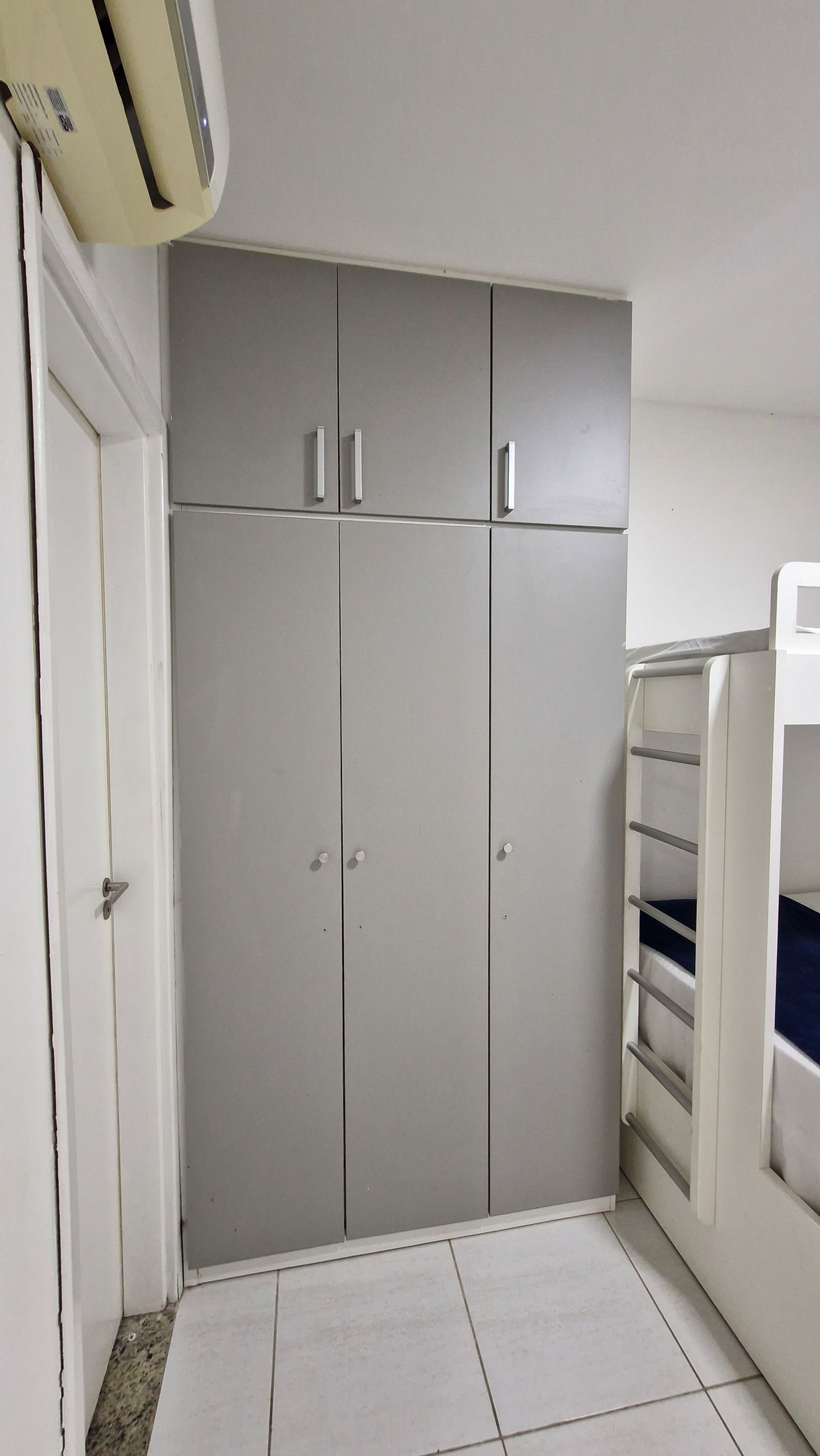 Une pièce avec une armoire grise, une porte blanche et un radiateur blanc.