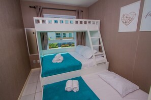 Une chambre avec un lit superposé, deux lits, une fenêtre avec vue et une échelle.