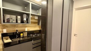 A modern kitchen with a built-in stove, black countertops, and a large refrigerator. - Flat em Porto de Galinhas - Muro Alto Clube (Ipojuca)