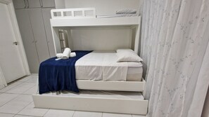 Uma cama beliche com estrutura branca, cobertor azul e travesseiro branco.