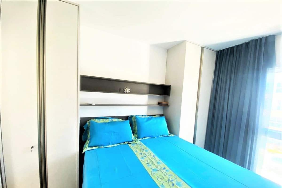 Une chambre d’hôtel avec un lit, une armoire et une fenêtre avec des rideaux.