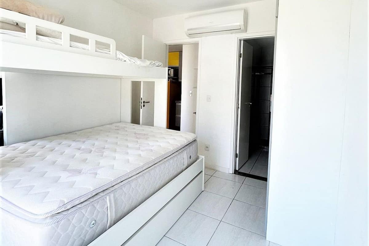 Une chambre avec un lit superposé, une armoire et un appareil de climatisation.