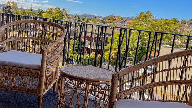 Un balcón con mobiliario de mimbre y vistas a una zona residencial.