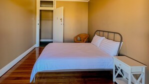 Un dormitorio con cama, mesita de noche, silla y ventilador de techo.