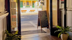 Entrada de un hotel con piso de madera, un letrero de salida verde e información sobre un evento.