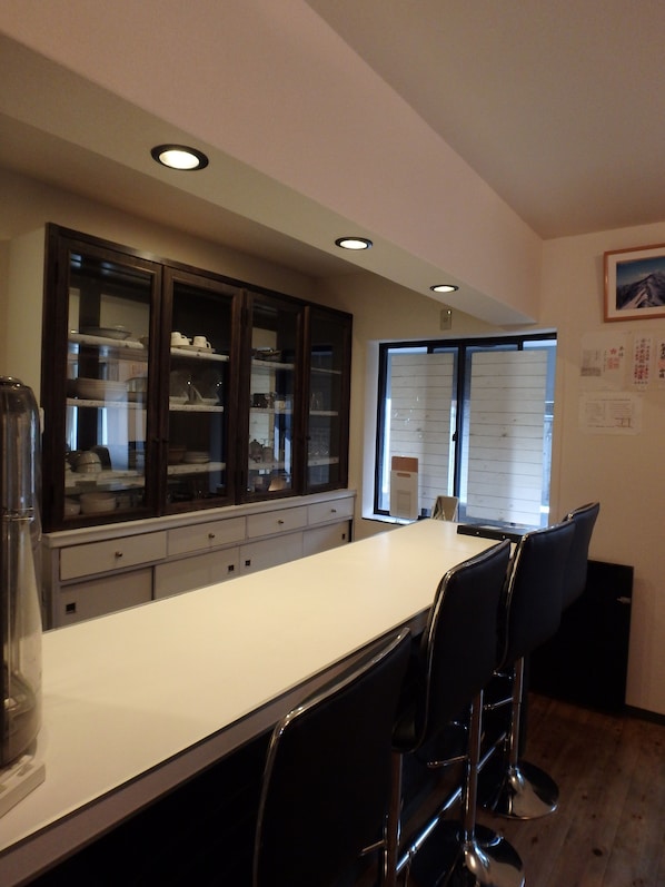 Una cocina con una encimera larga, taburetes de bar y un refrigerador.