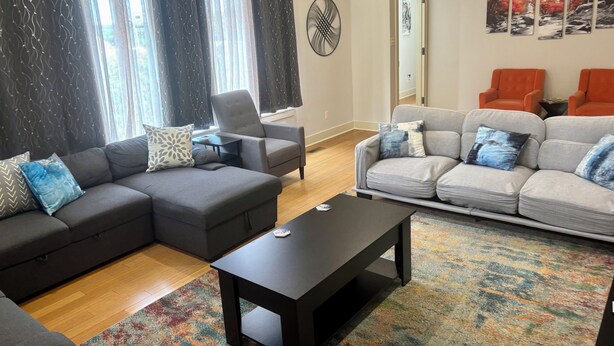 A modern living room with a sectional sofa, a grey couch, and a black coffee table.