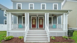 A two-story house with a front porch, two red doors, and a white railing. - Two Classy Homes - Sleeps 20, Steps from the Beach (Hampton)