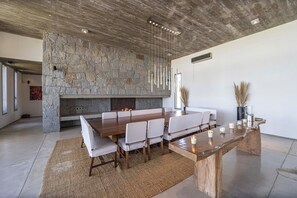 Una cocina moderna con pared de piedra, una mesa de comedor de madera grande y sillas blancas.