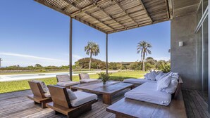 Un espacio de estar al aire libre cubierto con muebles de madera y vistas al paisaje.