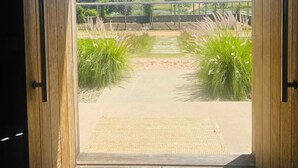 Una puerta de madera que da a un sendero pavimentado con vistas al paisaje rural.
