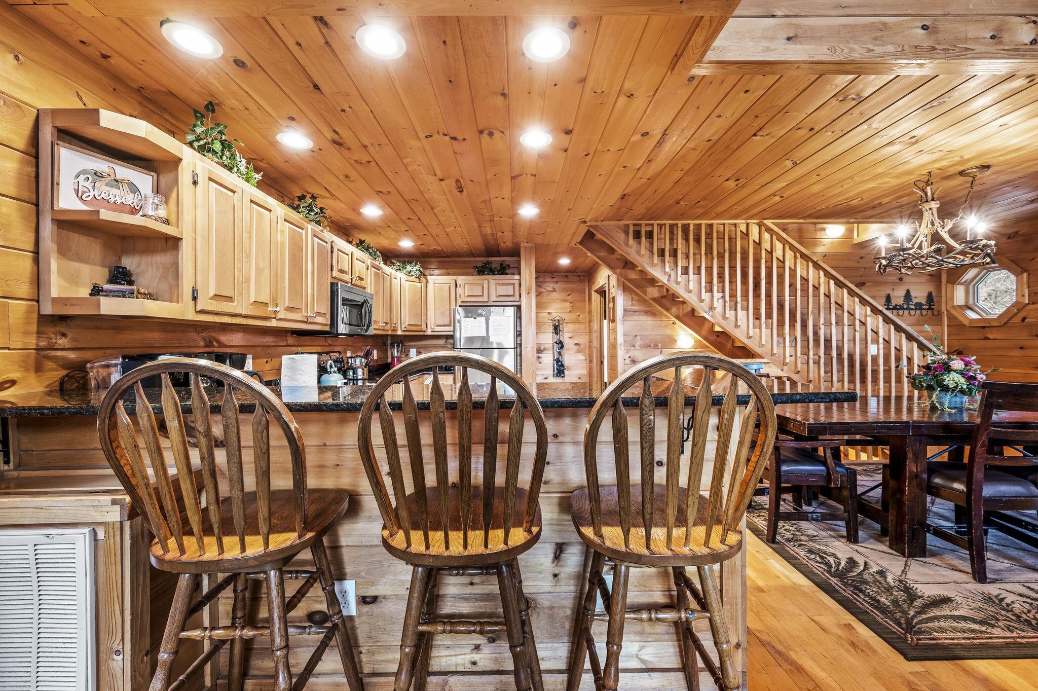 A wooden interior with a kitchen, dining area, and staircase.