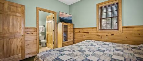 Une chambre à coucher avec une tête de lit en bois, une couvre-lit matelassé, une fenêtre avec des stores et une armoire en bois.