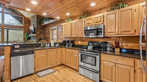 Una cocina moderna con armarios de madera, electrodomésticos de acero inoxidable y una pared de acento de piedra.
