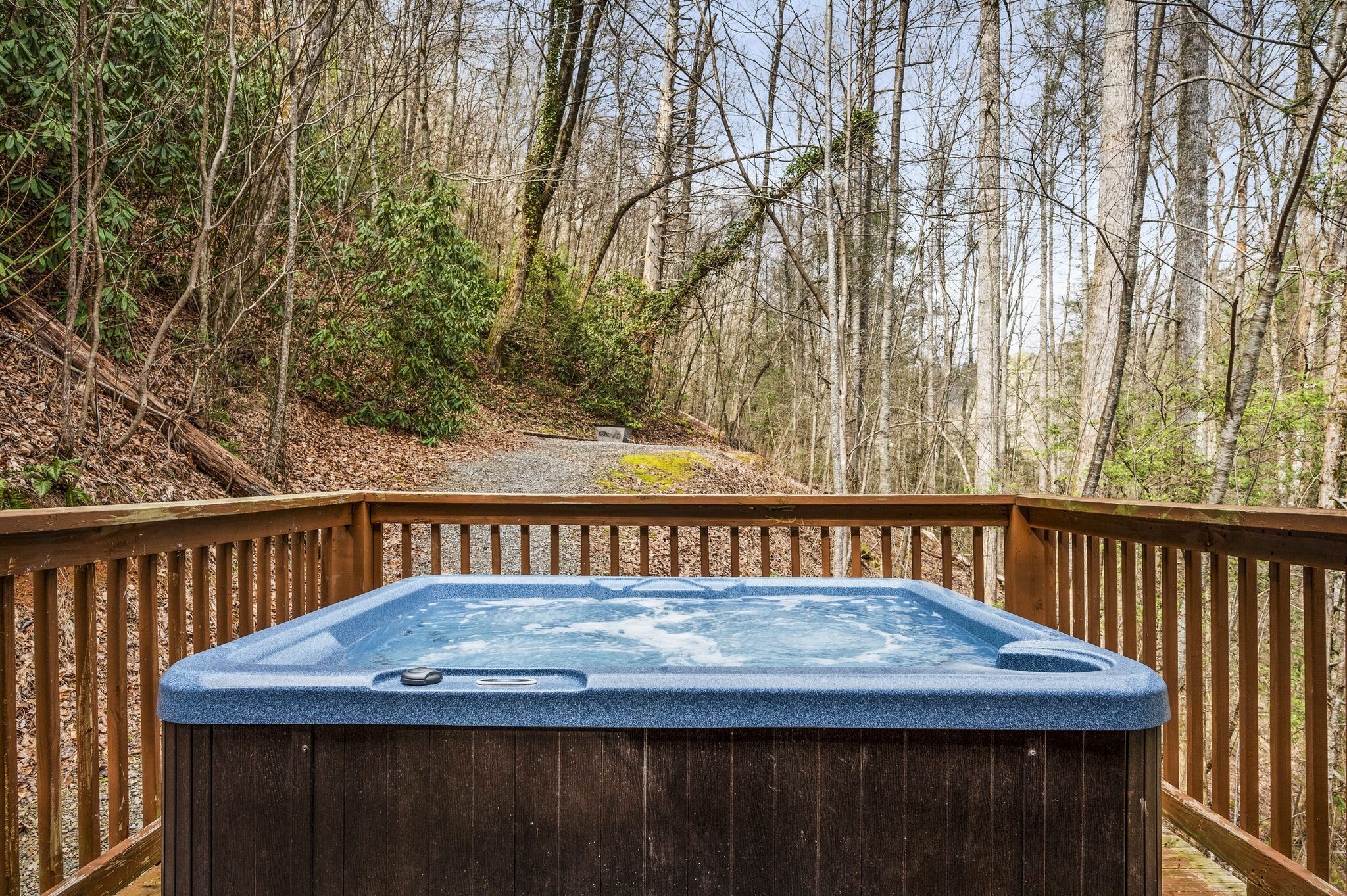 A hot tub on a wooden deck surrounded by a forest.