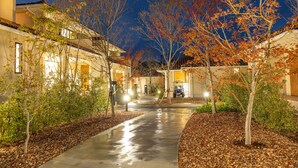 A residential street at night with houses on either side, a wet driveway, and autumn-colored trees. - Setouchi golf resort Villa (Takehara)