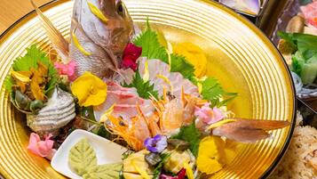 A seafood platter with various types of fish and shellfish, garnished with herbs and flowers.