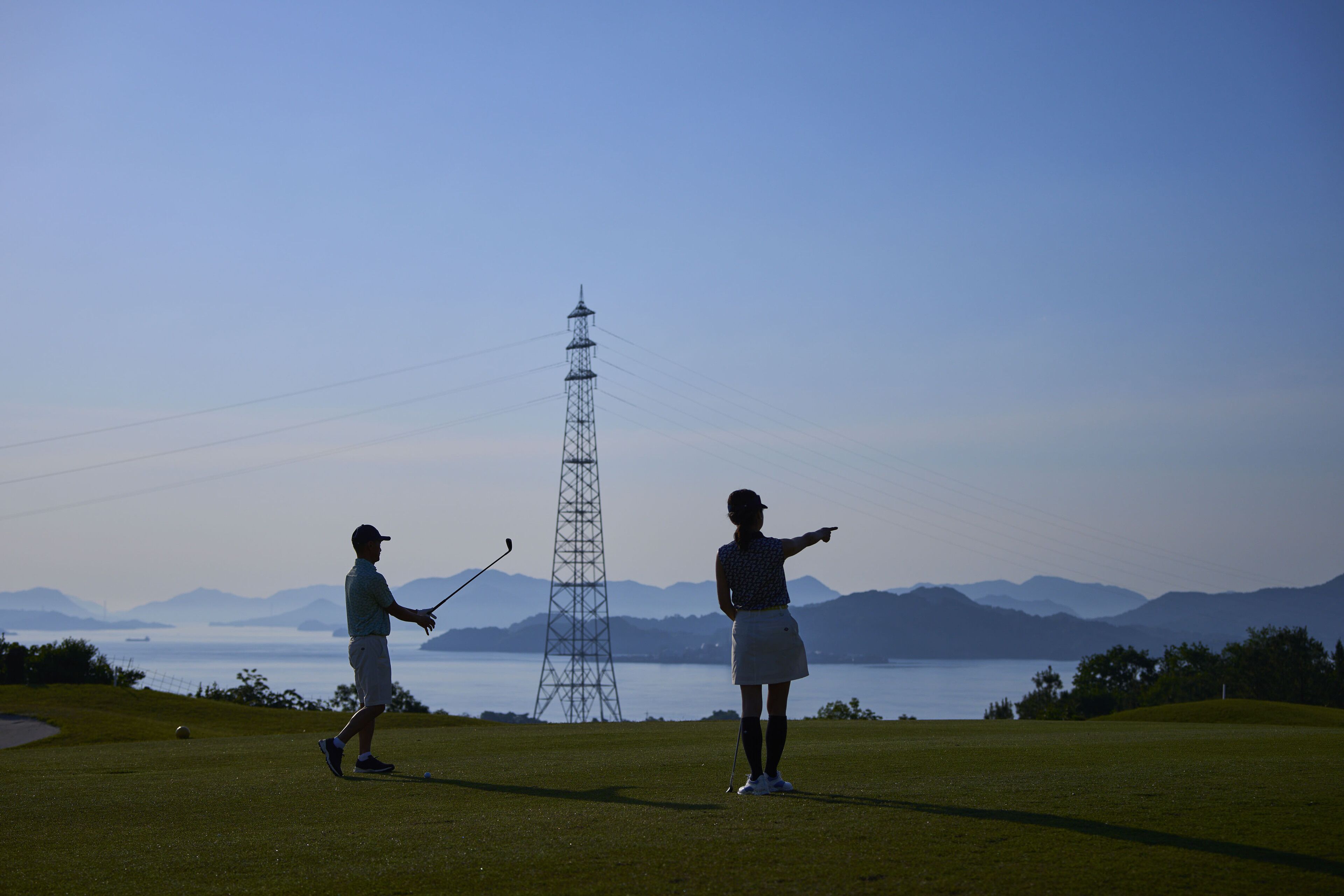 A golf course with a clear view of the water and mountains in the background.