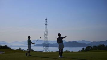 A golf course with a clear view of the water and mountains in the background.