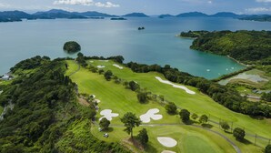 A golf course with sand bunkers, a water body, and distant mountains. - Setouchi golf resort Villa (Takehara)