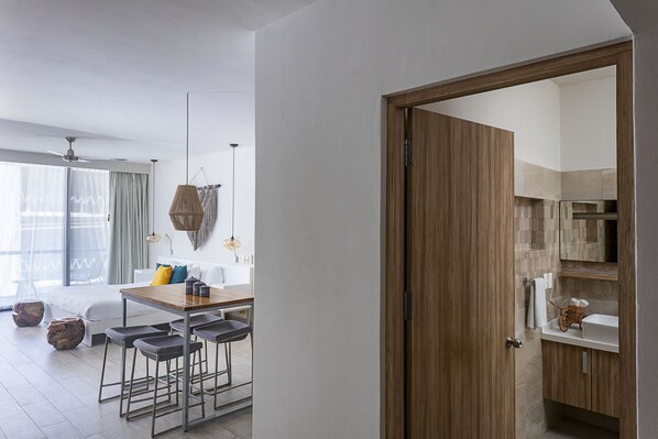 Cozinha moderna com porta de madeira, área de jantar com mesa e banquetas, e uma janela grande com cortinas.