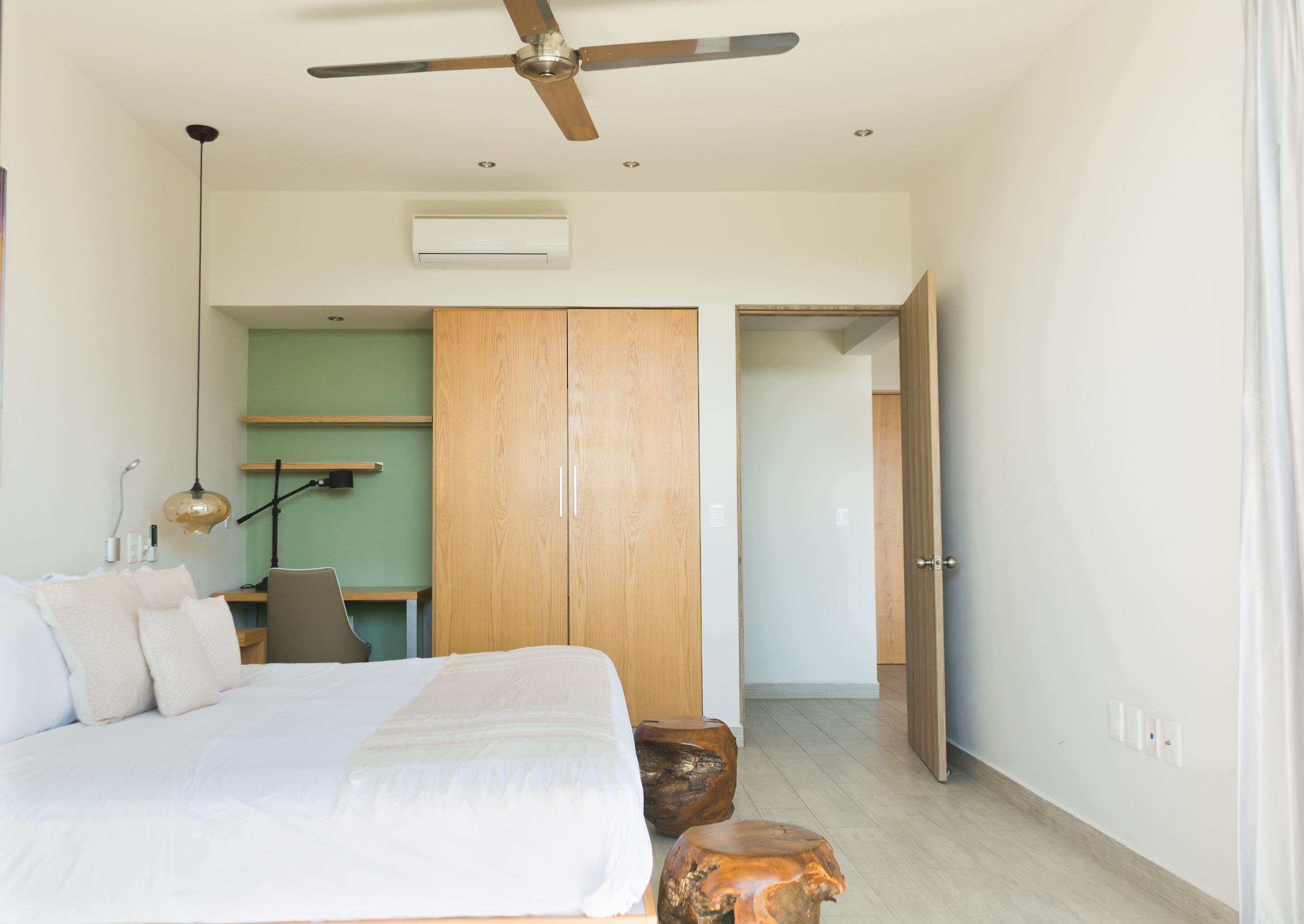 A modern bedroom with a bed, a desk, a wardrobe, and a ceiling fan.