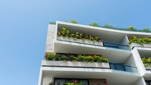 A modern multi-story building with balconies adorned with plants. - Opal Suites (Playa del Carmen)