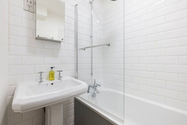 A bathroom with a white sink, mirror, and bathtub.