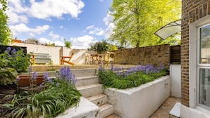 A garden with steps, a brick wall, and outdoor furniture.