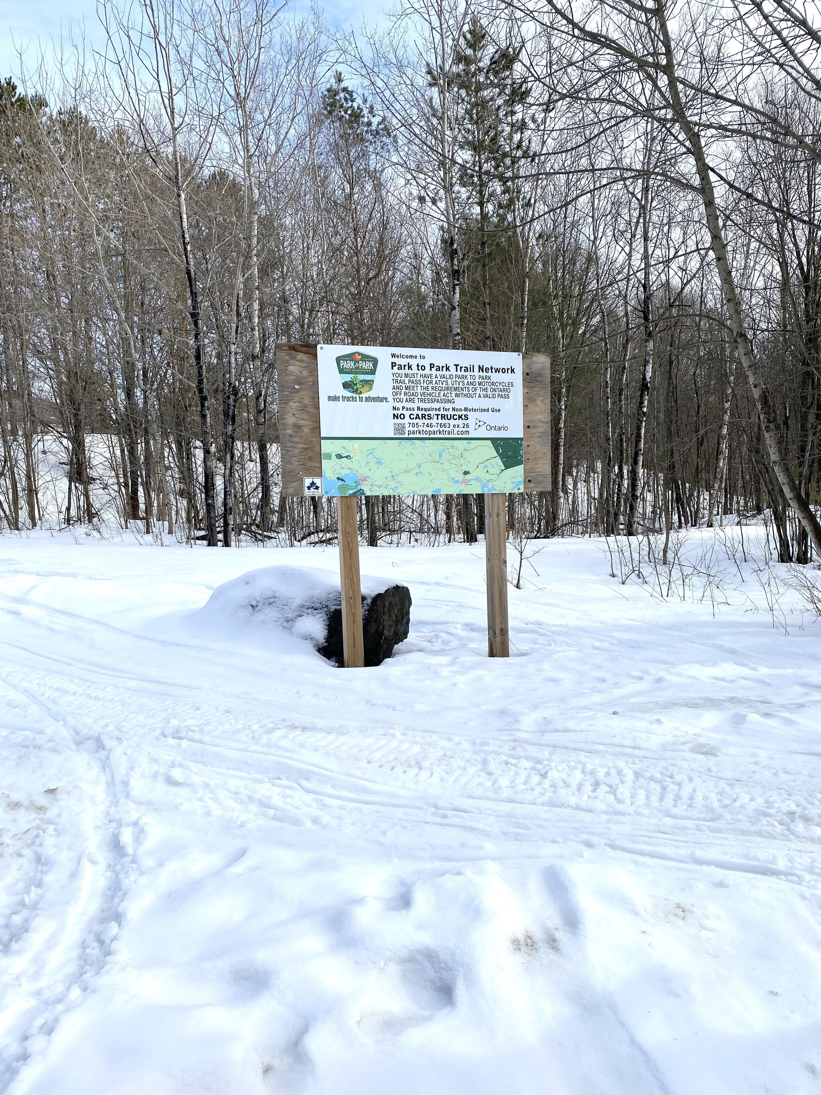 Ein Schild in einem verschneiten Parkbereich mit einer Karte und Informationen zum Park-Park-Wanderweg-Netzwerk.