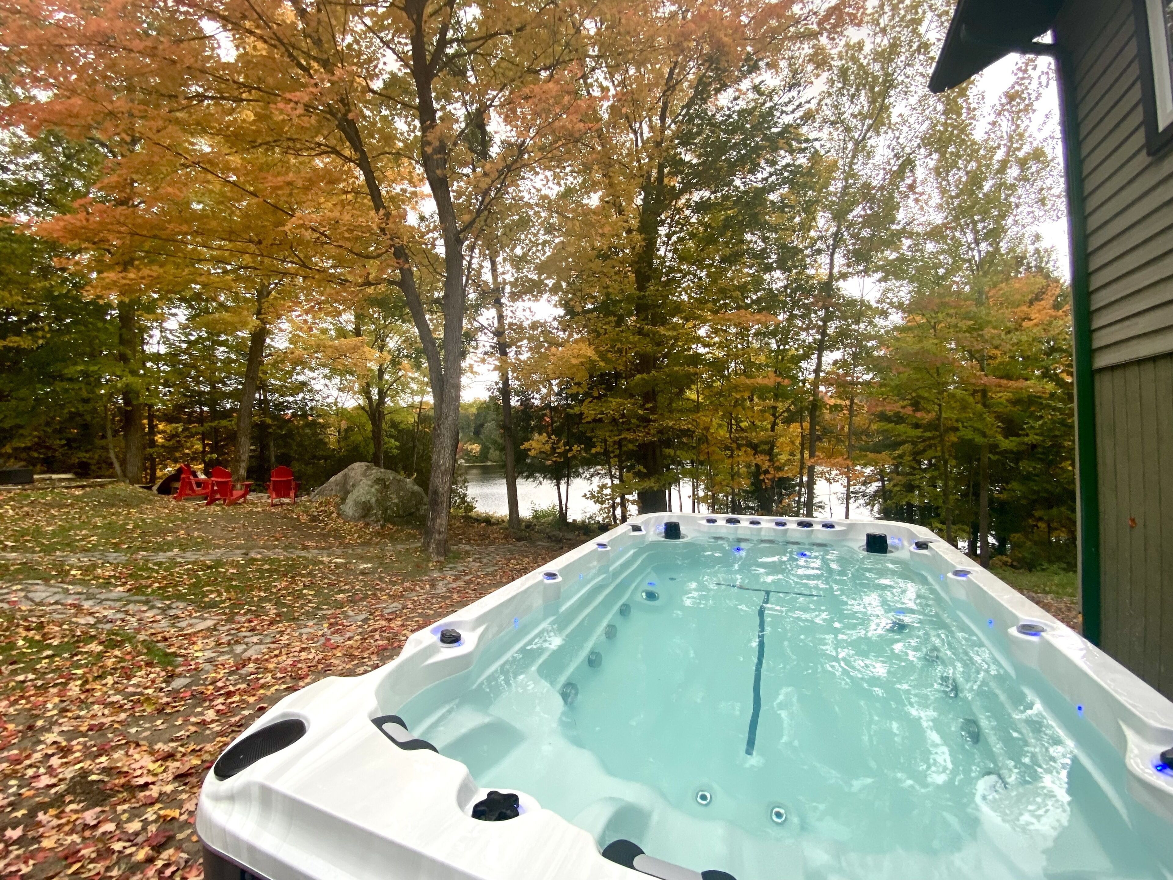 Een hottub met uitzicht op een meer en herfstbomen.