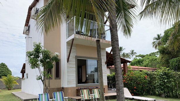 A two-story building with a balcony, surrounded by greenery and palm trees. - Casa D'Jhú (Vera Cruz)