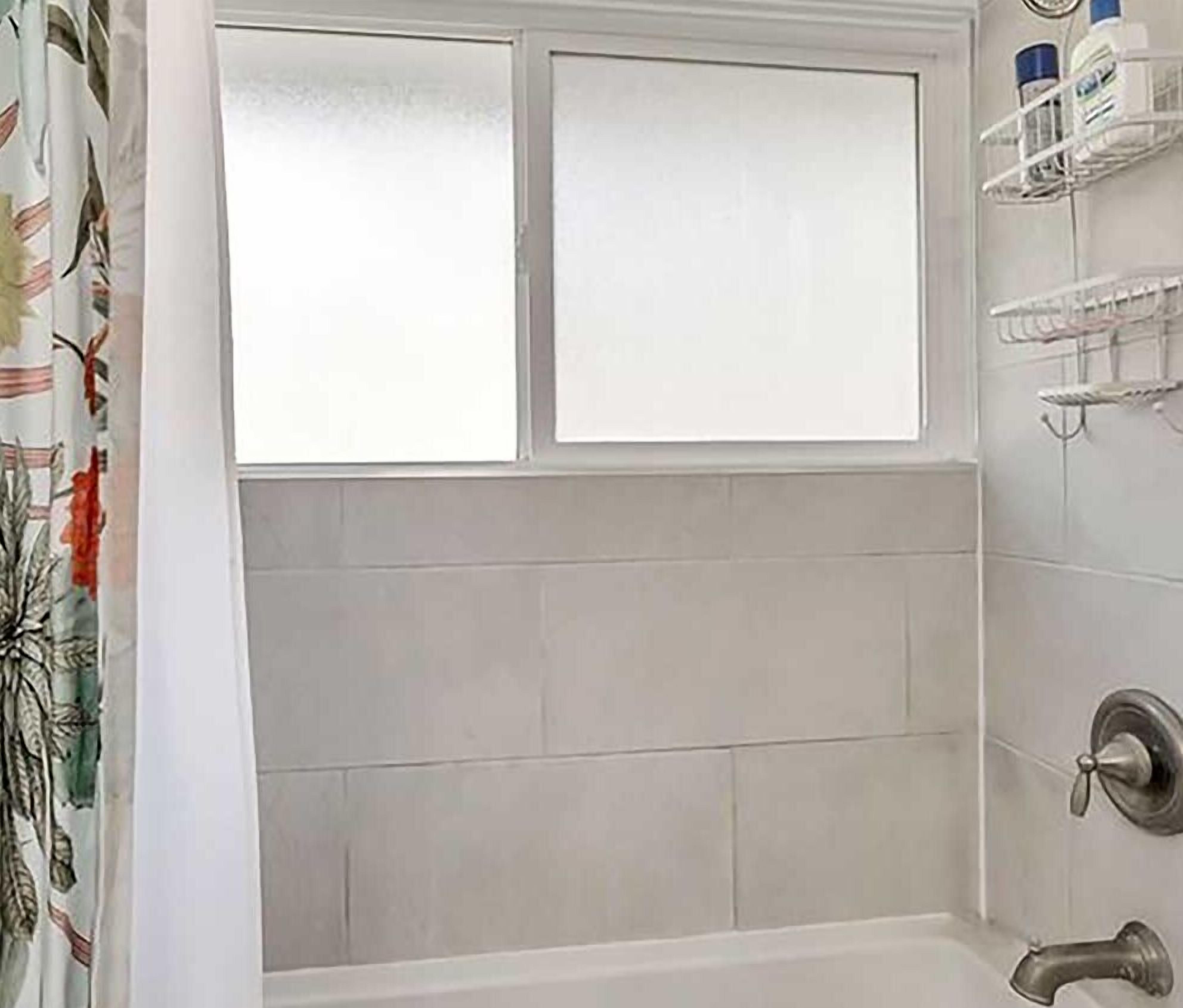 A bathroom with a bathtub, a window, and a shower area.