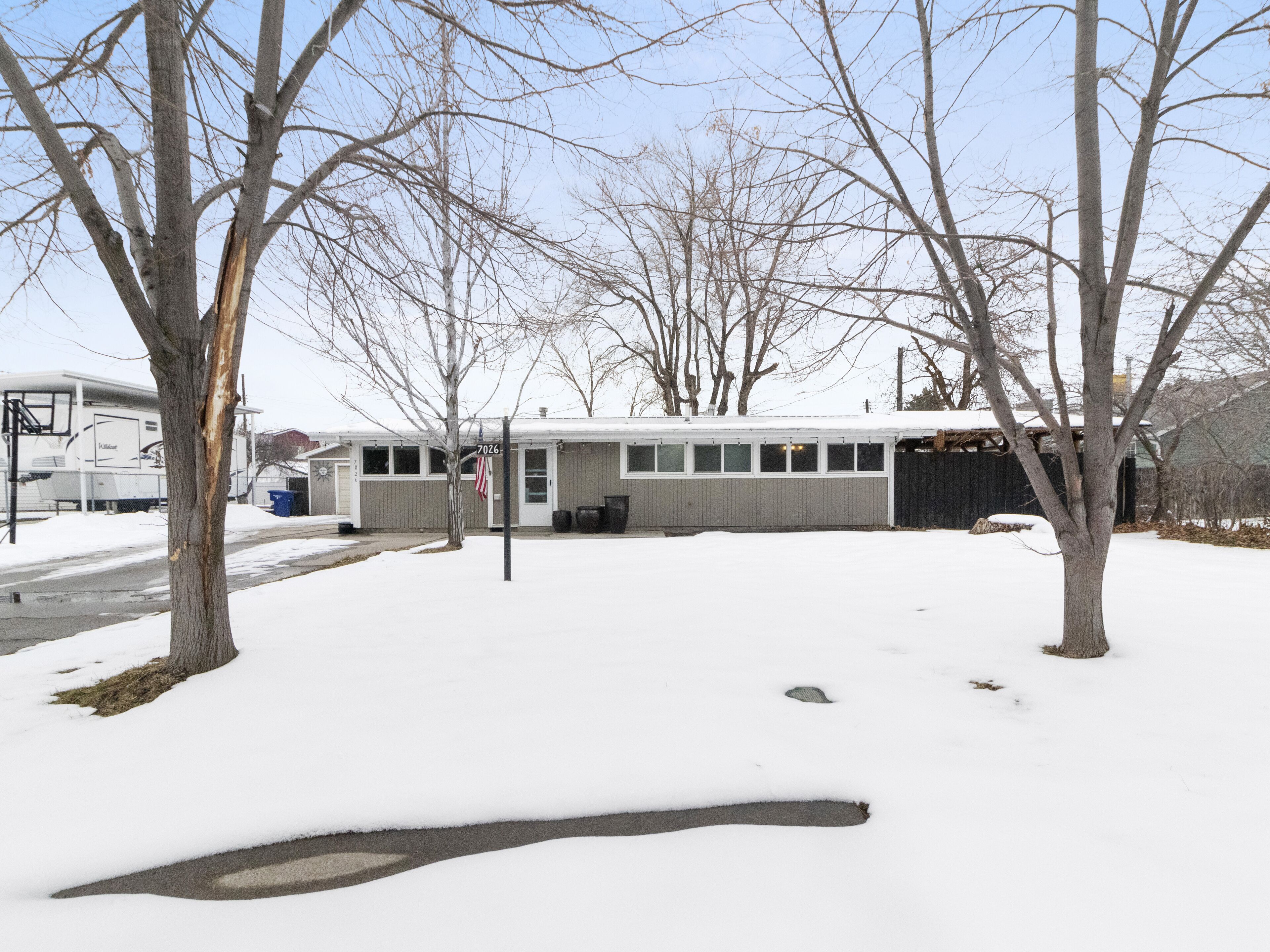 A residential building with a garage, a covered driveway, and a snow-covered landscape.