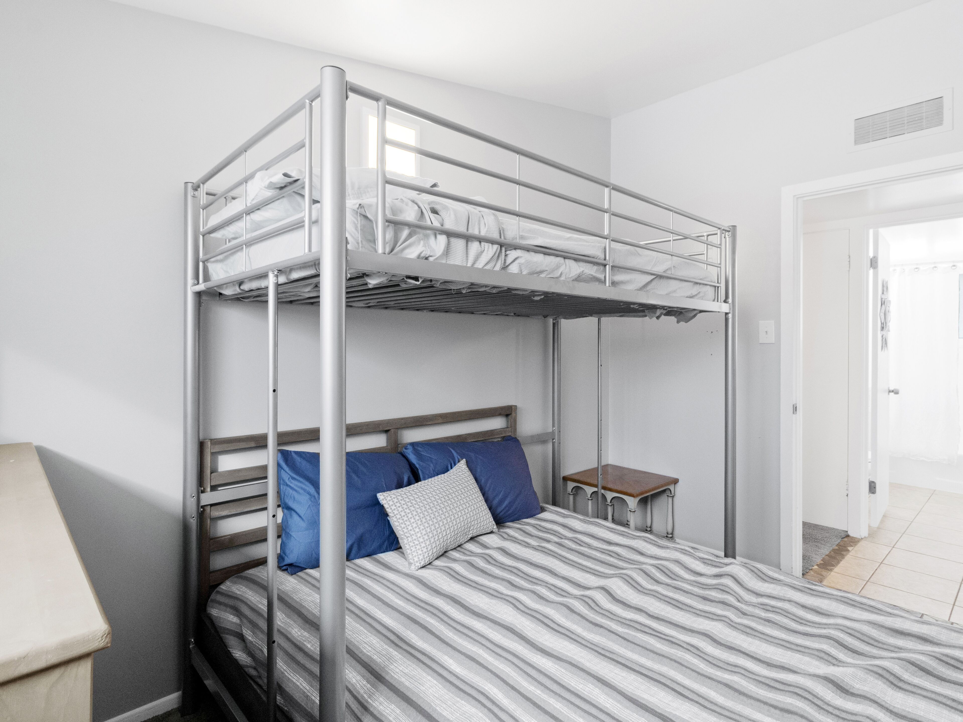 A bunk bed with a metal frame, a wooden headboard, and a striped bedspread.