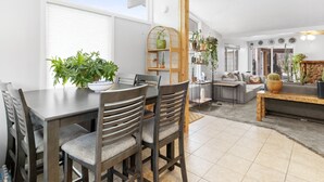 A dining area with a table and chairs, a plant on the table, and a shelving unit with plants.