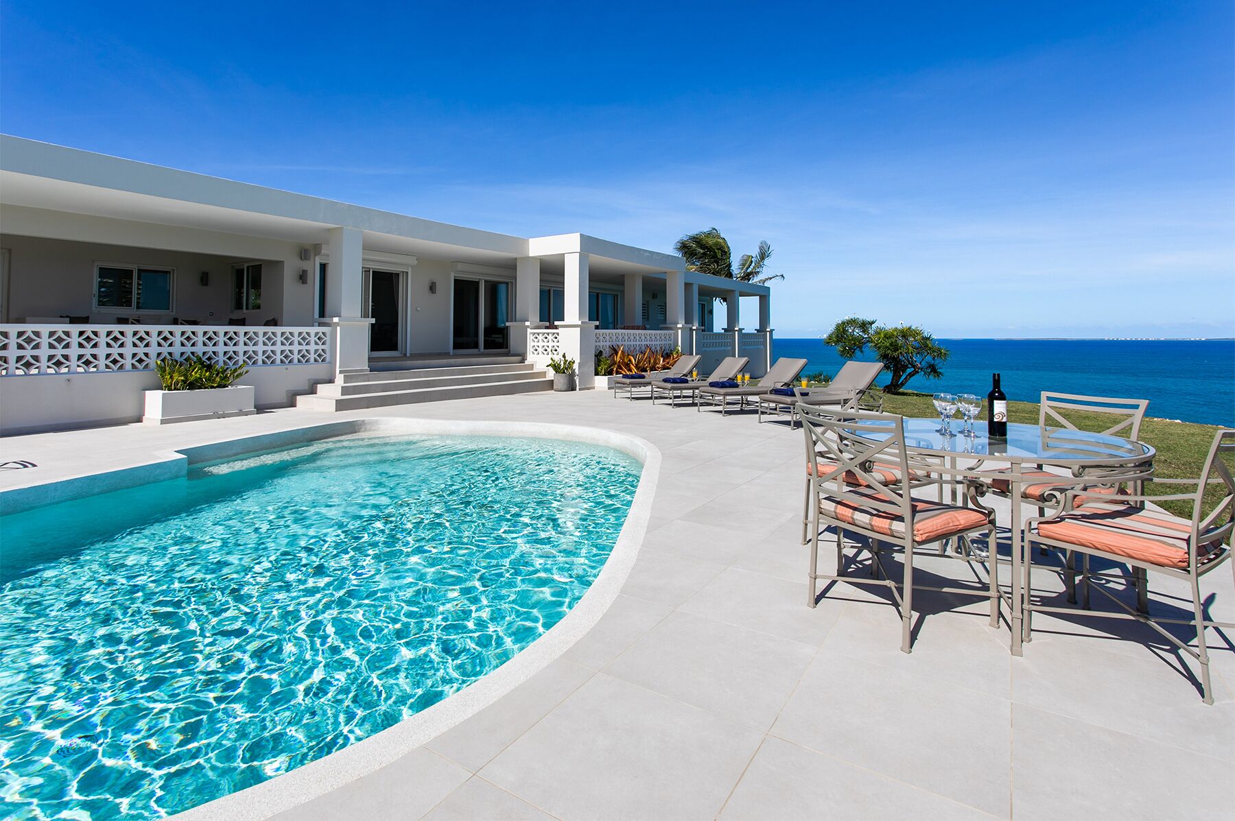 A modern resort with a swimming pool, outdoor seating, and a view of the ocean.